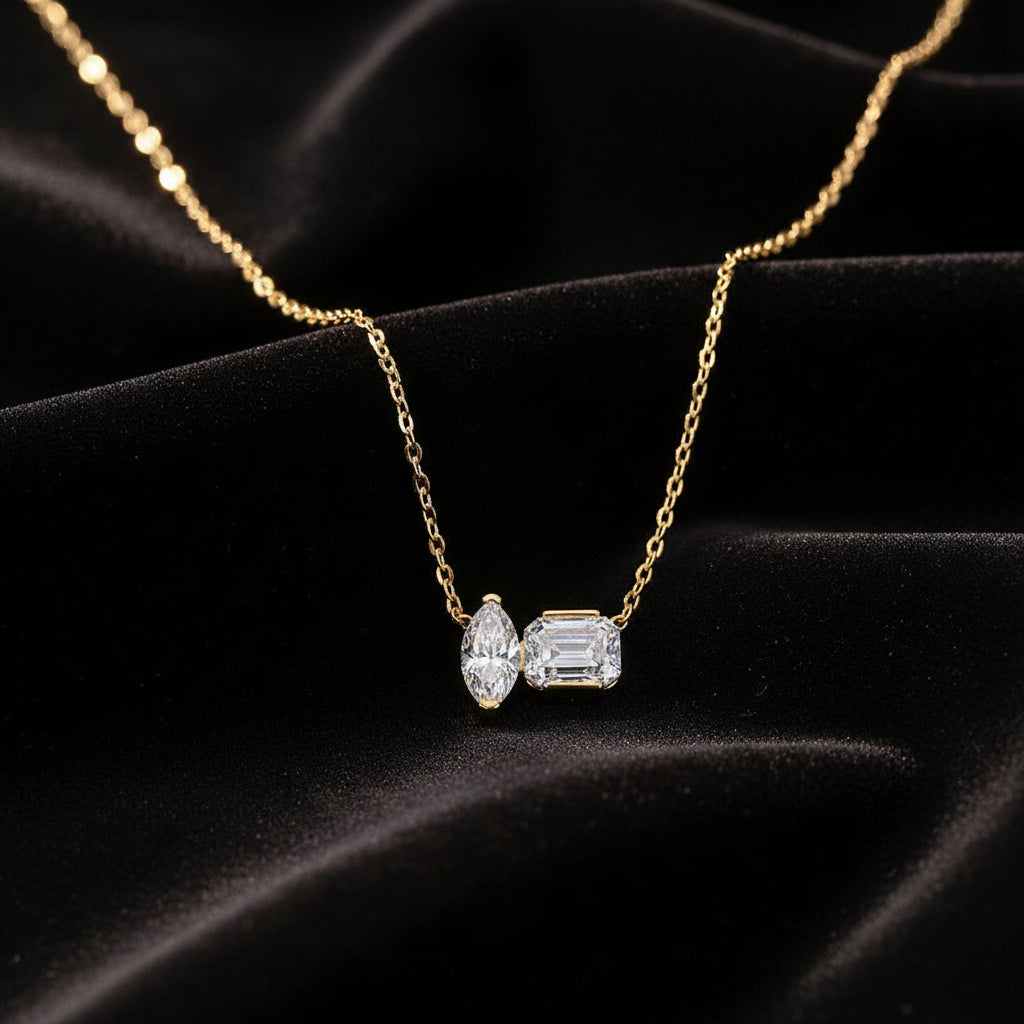 Gold necklace with diamond pendants on a light gray background
