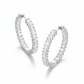 Pair of silver hoop earrings with clear gemstones on a beige fabric background