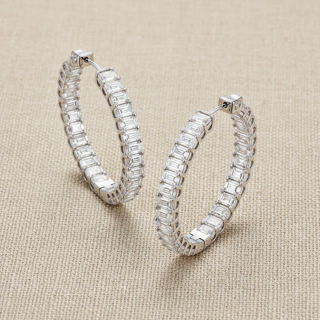 A pair of silver hoop earrings paved with baguette-cut clear stones, displayed on a clean white background.